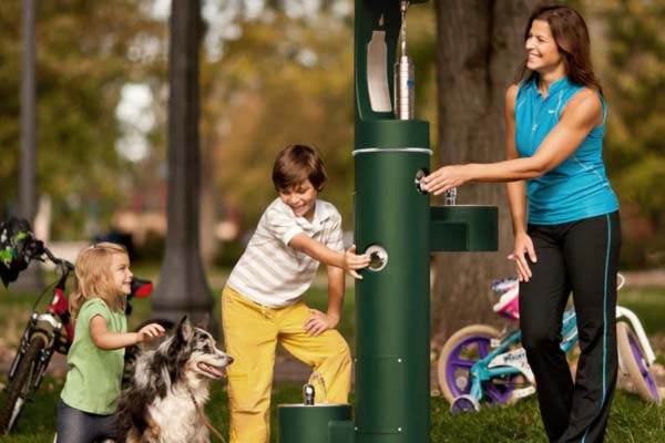 Cilvēki izmanto dzeramā ūdens staciju ārpus telpām